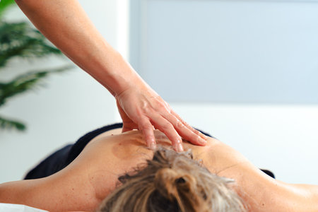 Unrecognizable therapist giving relaxing leg massage to client in professional spa settingの写真素材