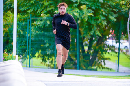Young man running on city bridge, wearing black sportswear during morning jog.