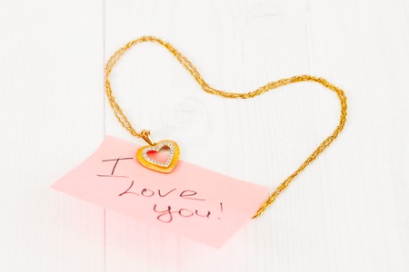 gold jewelry in the shape of a heart on white boardsの写真素材