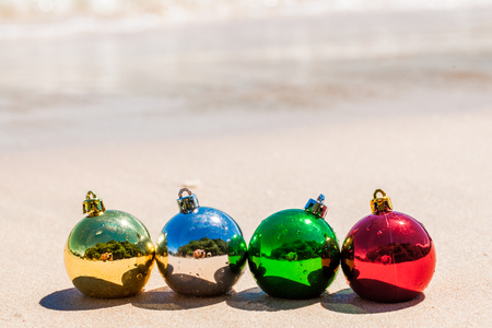 Four christmas decoration balls on sea beach sand on Phuket island, Thailand - travel X-mas and New Year holidays and vacation in tropicsの写真素材