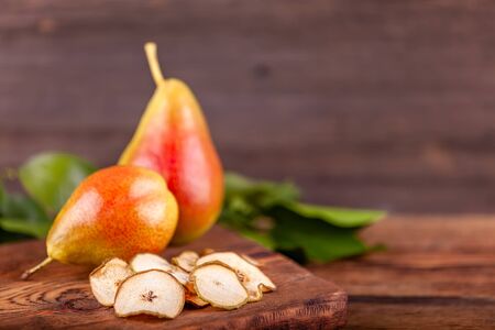 Two fresh red pears with dryed chips on wooden backgroundの写真素材