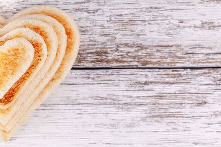 Stack of toasted bread hearts on wooden table, concept of support in big familyの写真素材