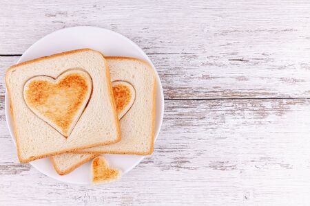 Toasted bread sliced hearts on wooden table, concept of happy family breakfastの写真素材
