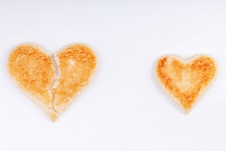 Bread toast broken heart with whole heart together on white backgroundの写真素材