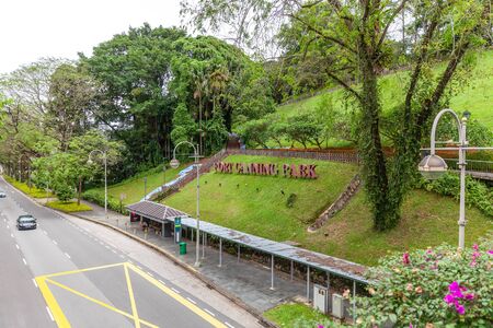 Fort Canning Park Sign on Green Lawn with Tropical Trees near the Road with Carsのeditorial素材
