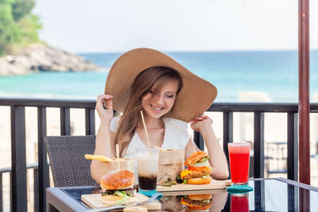 Travel Woman with Fast-food, Burgers, Coffee and Juice Drinks at Outdoor Cafeの写真素材