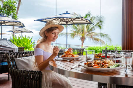 Attractive woman eats italian pasta in outdoor restaurant or cafe, prepared foodの写真素材