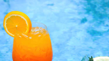 Cold non-alcoholic cocktail with ice and slice of orange and blue swimming poolの写真素材