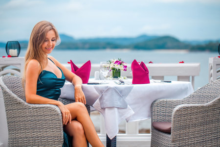 Beautiful young woman in elegant evening dress in restaurant at luxury hotelの写真素材