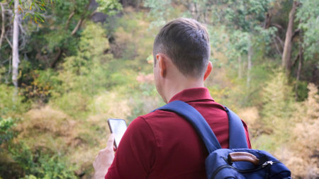 Male traveler blogger with backpack in nature filming video on smartphone cameraの写真素材