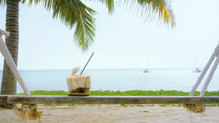 Fresh Thai coconut water cocktail on the beach with beautiful sea and palm trees