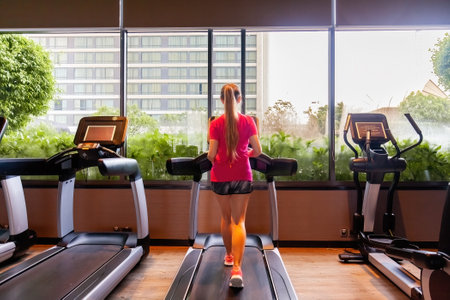 Young woman in sportswear running on treadmill in modern gym
