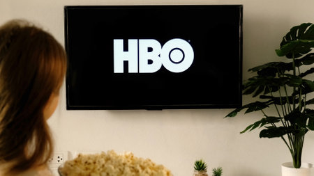 Woman holding a TV remote and watch HBO show on screenのeditorial素材