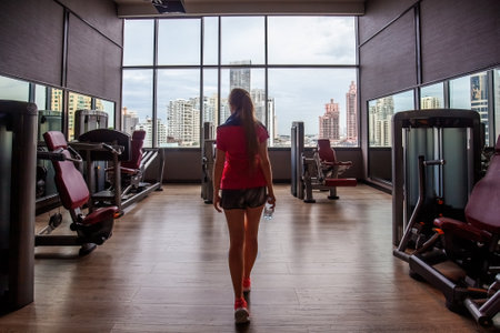 Fitness girl in sportswear in modern gym with skyscrapers view
