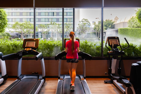 Young woman in sportswear running on treadmill in modern gymの写真素材