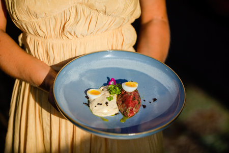 Woman hold a plate with tartar beef, sauce and boiled quail eggsの写真素材