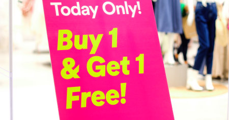 Bright pink sign with yellow words Buy 1 Get 1 Free in shopping mallの写真素材
