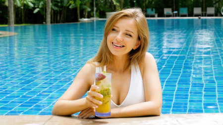 Beautiful woman in white swimsuit lounging in swimming pool, drink cocktail