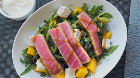 Raw Tuna sashimi salad with a mix of fresh fruit, cheese, and arugula