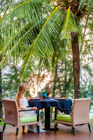 Woman on dinner in outdoor restaurant with tropical palm treesの写真素材