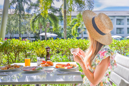 Young woman in dress sits at restaurant, enjoy traditional food of Thailandの写真素材