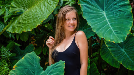 Beautiful woman in black swimsuit in a tropical setting during the summerの写真素材