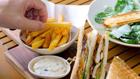 Man hand take a french fries from table with fast foodの写真素材