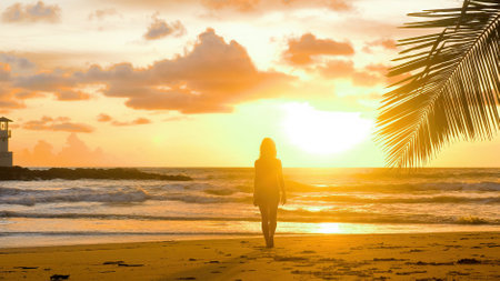 Young woman enjoy summer vacation holidays at ocean. Happy female tourist walk in romantic golden sunset lights with sea waves background. Girl walking barefoot at seaside on sandy beach. Slow motionの写真素材