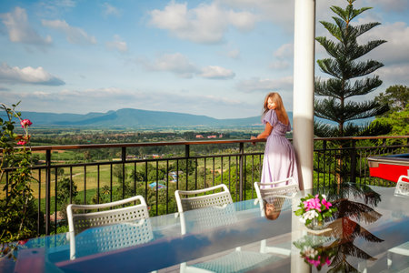 Woman on vacation enjoys beautiful mountain view from a balconyの写真素材