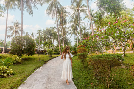 Young woman in a stylish dress enjoys a summer vacation at a tropical resortの写真素材