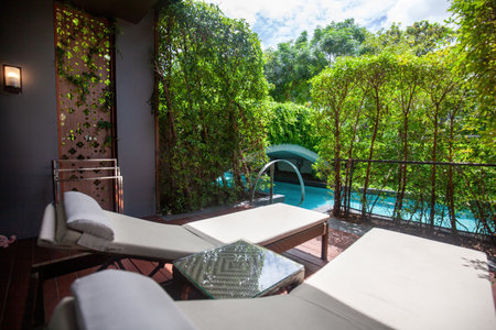 Wooden deck with two lounge chairs, overlooking the poolの写真素材