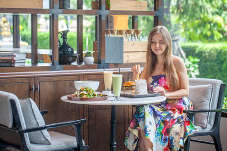 Relaxed female diner in patterned summer dress examines menuの写真素材