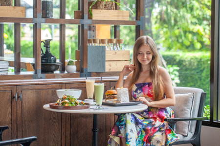 Smiling woman poised with healthy smoothie and light lunchの写真素材