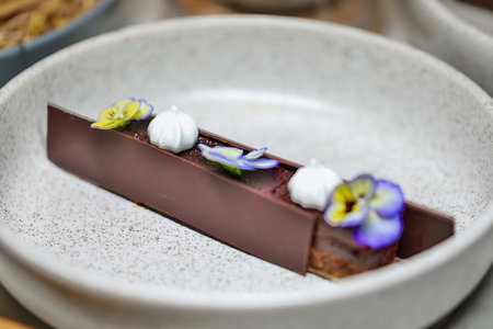 Gourmet chocolate dessert beautifully garnished with edible flowers. Fine dining and patisserie.