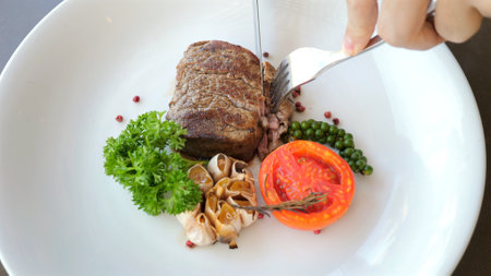 Grilled steak on white plate with roasted tomato, garlicの写真素材