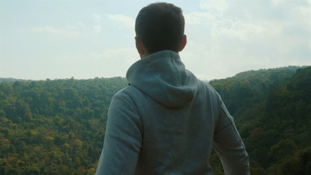 Person standing on edge of forest, looking out at lush green scenery,の写真素材
