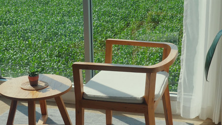 Cozy wooden chair and small table with potted plant by window,の写真素材