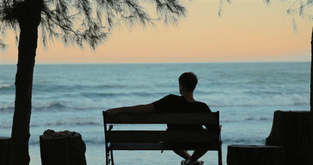 Man relaxing on bench by ocean, silhouette, sunset, tranquil scene,の写真素材
