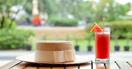 Straw hat and watermelon juice on outdoor wooden table in garden;の写真素材