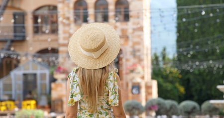 Woman in summer dress and straw hat admires view of rustic courtyard,の写真素材
