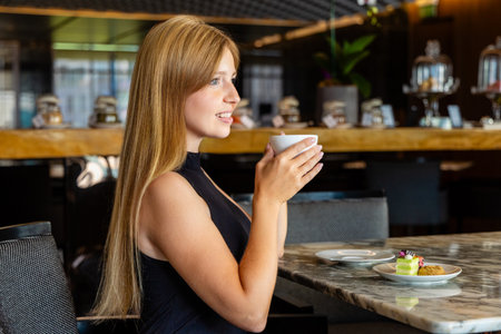 Woman enjoying coffee in modern cafe, seated at marble table,の写真素材