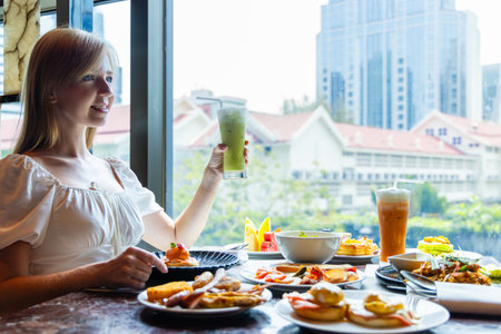 Woman enjoying brunch in urban cafe, window view. Fresh juice,の写真素材