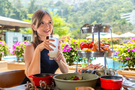 Young woman enjoying seafood and lemonade in outdoor restaurant,の写真素材