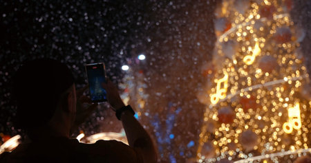 Person Filming Festive Christmas Lights with Smartphoneの写真素材