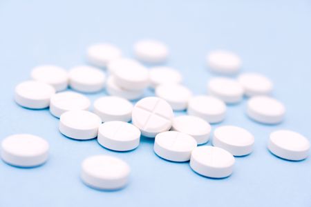 White medicine pills on light blue background