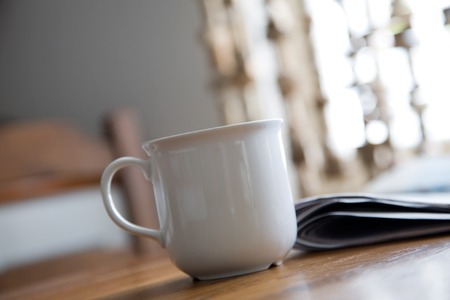 Cup of coffee and newspaper on kitchen tableの写真素材
