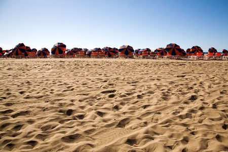 Long beach with chairs and colorful parasolsの写真素材