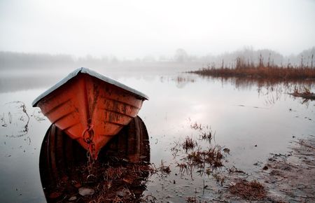 Orange boat in beautiful morning misty light