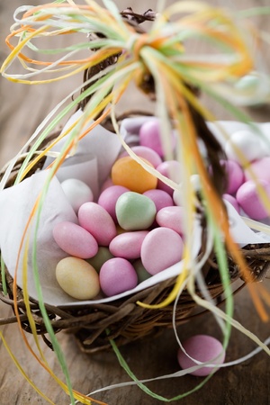 Colorful easter candy in brown basket with ribbon