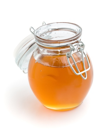 Liquid honey in small glass jar, white isolated backgroundの写真素材